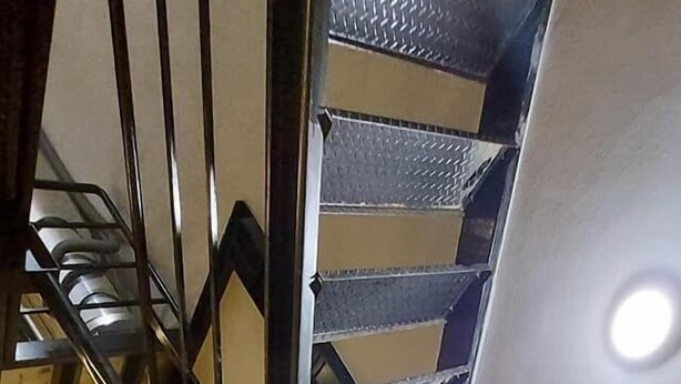 A wooden staircase with metal railings and a textured wall. - A BA LI BI Duck (Tainan)