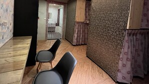 A room with a wooden floor, two black chairs, a patterned wall, and a door with a curtain. - A BA LI BI Duck (Tainan)