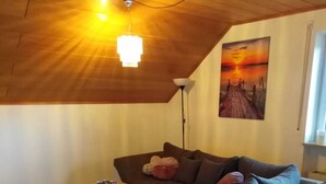 Una sala de estar moderna con techo de madera, un sofá blanco, una mesita auxiliar y una lámpara de pie.