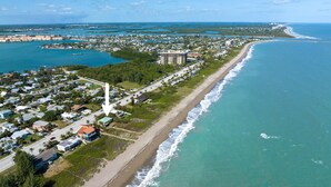 An aerial view of a coastal town with a beachfront, residential areas, and a prominent tall building. - Private Beachfront House (Fort Pierce)