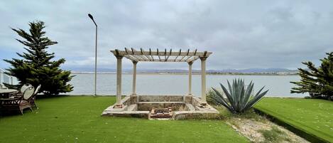 A pergola with a view of a lake and mountains in the background.