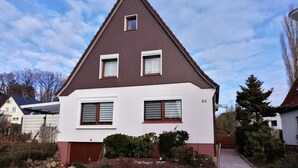 A two-story house with a brown roof, white walls, and a small front porch. - FEWO in ruhiger Lage (Niedersachsen - Buxtehude)