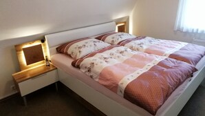 A bed with a headboard, bedside tables, and a window with curtains. - FEWO in ruhiger Lage (Niedersachsen - Buxtehude)