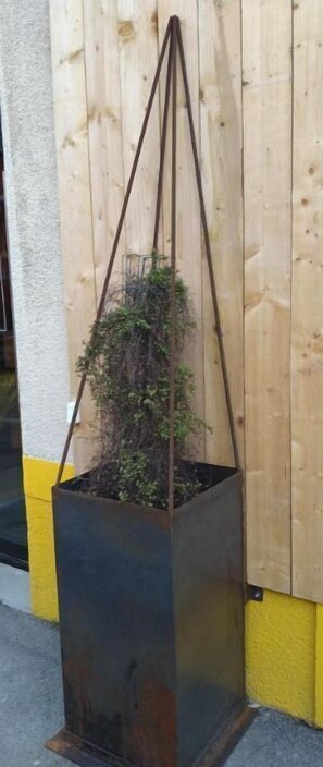 A planter box with a plant, placed against a wooden fence. - Appart. de Ville Quartier Dynamique (Nantes)