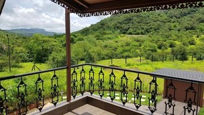 A balcony with wrought iron railings and a view of a lush green landscape with trees and hills. - Royal Villa with Private pool (Lonavala)