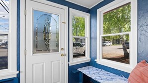 Une pièce avec une porte blanche et une fenêtre donnant sur des voitures garées et des arbres.