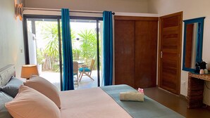 Un dormitorio con cama, mesita de noche, lámpara, ventana con cortinas y vistas al exterior.