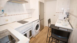 Une cuisine compacte équipée d’un lave-linge, d’un four à micro-ondes et d’un évier.