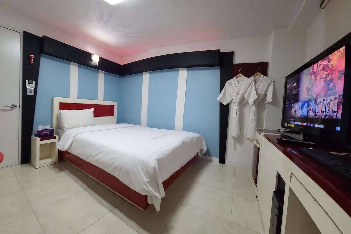 A hotel room with a bed, a TV, and a desk with a computer.