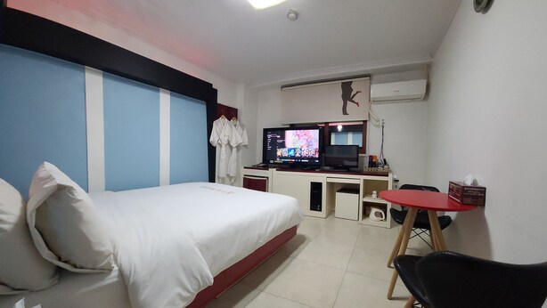 A hotel room with a bed, a desk with a computer, a TV, and a small table. - Dream Motel (Gwangju)