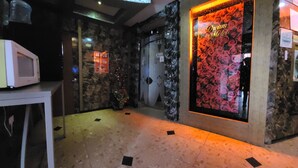 A hallway with a stone wall, a door with a 'Dream Motel' sign, a 'Netflix' sign, and a microwave on a table. - Dream Motel (Gwangju)