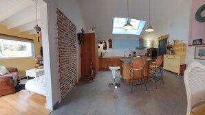 A modern kitchen with a central island, a dining area with wicker chairs, and a living room with a leather sofa. - Very pleasant family home in Saint-Enogat Dinard (Dinard)