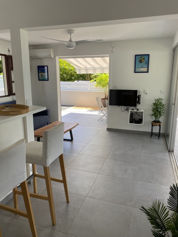 A modern living room with a TV, seating area, and a balcony with a view.