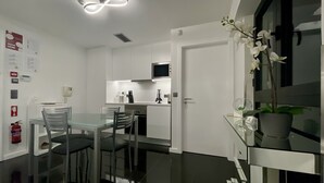 Ett modernt kök med vita skåp, en rostfri köksfläkt och ett matbord i glas med tillhörande stolar.