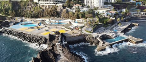 NĂ€ra stranden, svart sandstrand, solstolar och parasoller