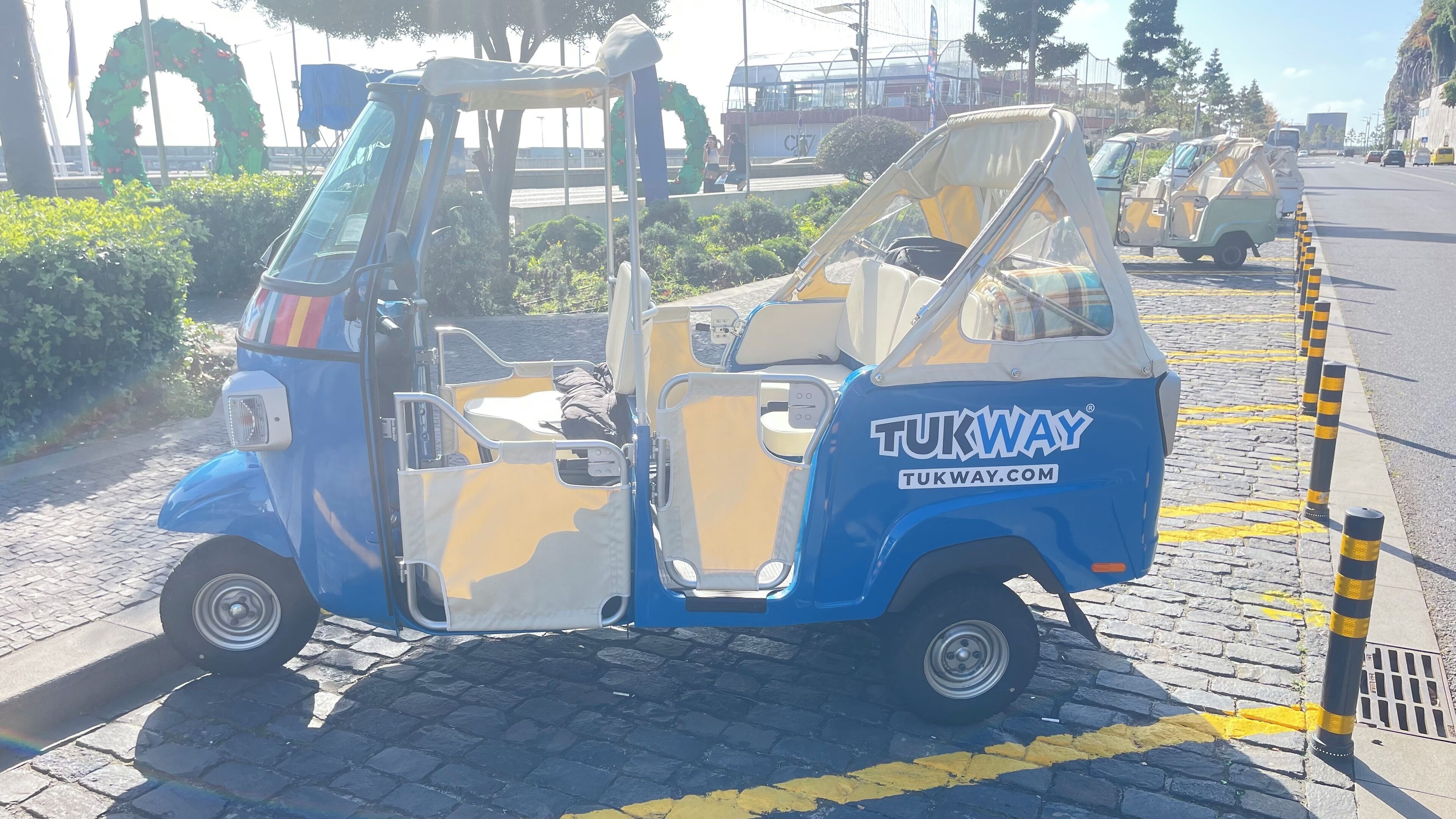 A tukway vehicle parked on a cobblestone street.