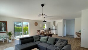 A modern living room with a sectional sofa, a dining area, and a kitchen.