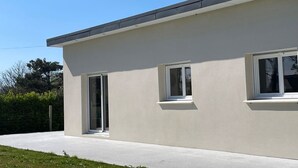 A modern building with a flat roof, large windows, and a concrete pathway.