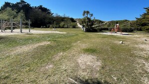 An outdoor area with a grassy field, a climbing structure, and a red chair.