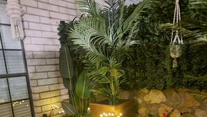 A brick planter with a large plant and decorative lights, surrounded by a stone wall and a brick border. - The Ritz serene spa sanctuary hot tub, mountain view, patio for the whole family (Las Cruces)
