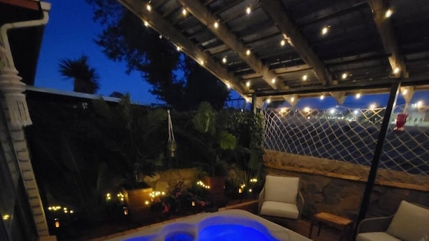 A hot tub with blue lighting, surrounded by outdoor seating and string lights. - The Ritz serene spa sanctuary hot tub, mountain view, patio for the whole family (Las Cruces)