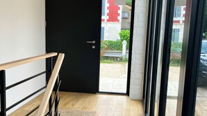 Um interior moderno com uma escada de madeira, uma porta preta e vista para o exterior.