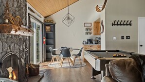 Un salon chaleureux avec une cheminée, une table de billard et un coin repas.