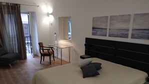 Een slaapkamer met een bed, bureau, stoel en een raam met gordijnen.