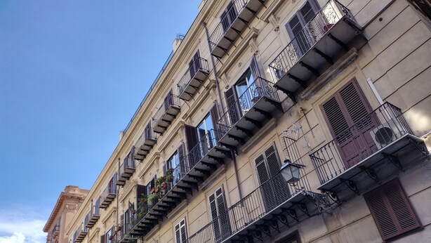 Een meerlaags gebouw met balkons, airconditioners en een bordje dat aangeeft dat het een bedrijf is dat Indiase kunst importeert.