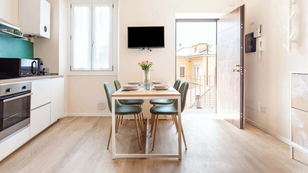 Una cocina moderna con una mesa de comedor, sillas y un televisor de pantalla plana.