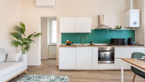 Una cocina moderna con armarios blancos, un salpicadero verde y un horno empotrado.