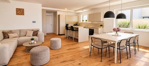 Un espace de vie moderne comprenant un canapé, un pouf, une table à manger et des chaises.