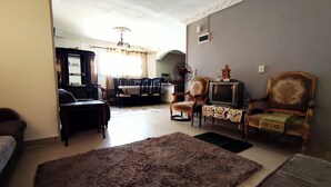Un salon comprenant un canapé, un téléviseur posé sur un meuble et un coin repas avec des chaises et une table.