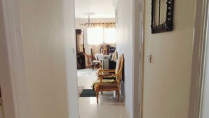 Un couloir mène à une salle à manger équipée d’une table et de chaises.