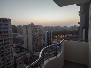 A high-rise building with multiple balconies, a view of the cityscape, and a sunset in the background. - WHOLE 140sqm Apartment in citycenter,
walk everywhere. On smouha & sporting view (الإسكندرية)
