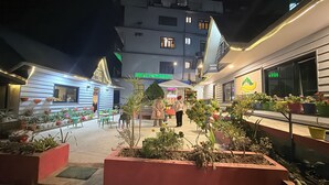Un patio de hotel con plantas en macetas, mobiliario exterior y un letrero que dice Hotel Pathibhara.