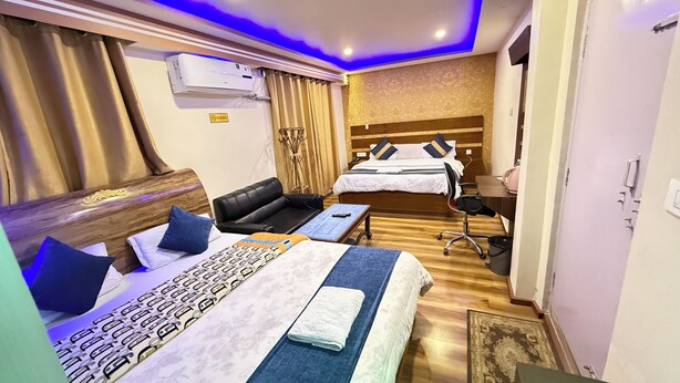 Habitación de hotel con dos camas, un escritorio, una silla, un sofá y un aire acondicionado.