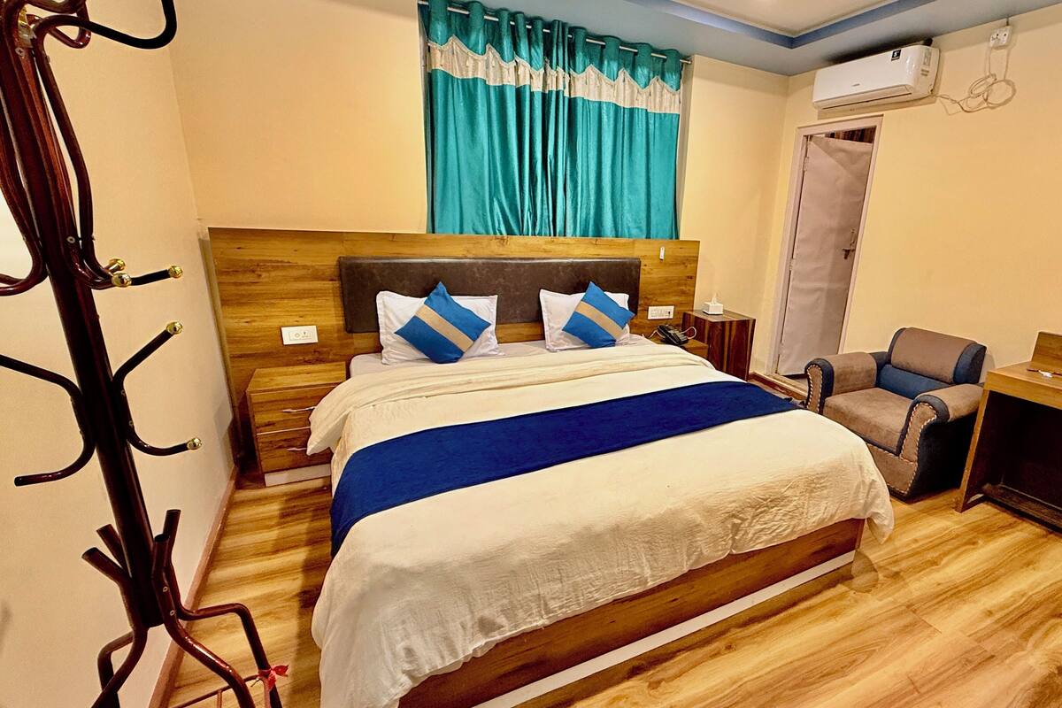 Una habitación de hotel con una cama de madera, un escritorio, una silla, un armario y una ventana con cortinas.