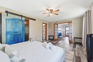 A hotel room with a bed, a ceiling fan, a bathroom with a shower, and a view of the outside. - 4BR Lakefront · Pier · Game Room · Sleeps 16+ (North Webster)