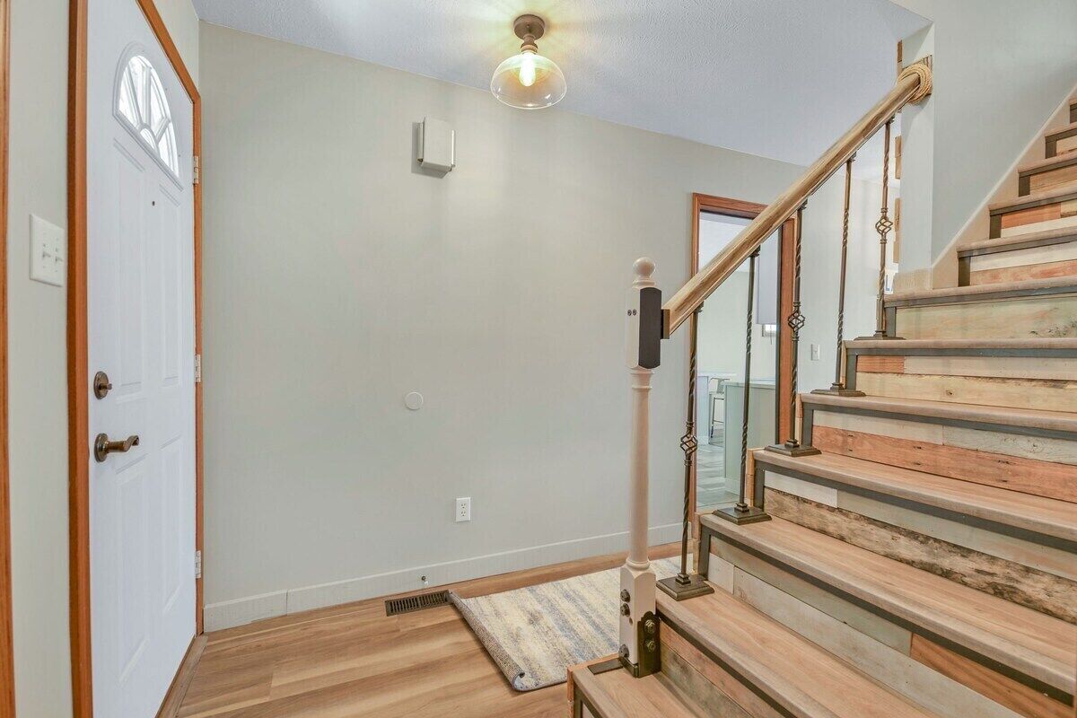 Un escalier avec des marches en bois et une rampe en verre, menant à l’étage supérieur.