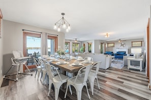 A spacious living area with a dining table set for six, surrounded by white chairs. - 4BR Lakefront · Pier · Game Room · Sleeps 16+ (North Webster)