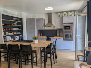 Une cuisine moderne dotée d’un îlot central, d’appareils électroménagers intégrés et de nombreux rangements.
