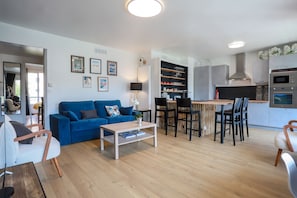 Un salon moderne avec un canapé bleu, une table basse et un coin repas comprenant des chaises et une petite table.