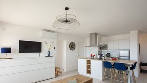 A modern kitchen with white cabinets, a built-in stove, and a dining area with blue chairs.