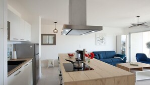 A modern kitchen with a central island, white cabinetry, and a stainless steel range hood.
