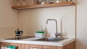 Et moderne køkken med en dobbeltvask, kaffemaskine, sæbedispenser og en hylde med krukker.