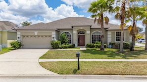 A residential house with a garage, a front yard with a mailbox, and a palm tree.