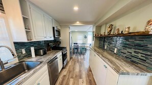 A modern kitchen with white cabinets, a stainless steel sink, and a wooden floor.