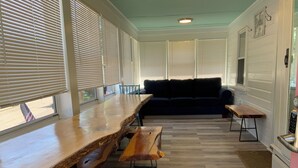 A long wooden table with benches, a dark blue sofa, and a kitchen area with a stove.