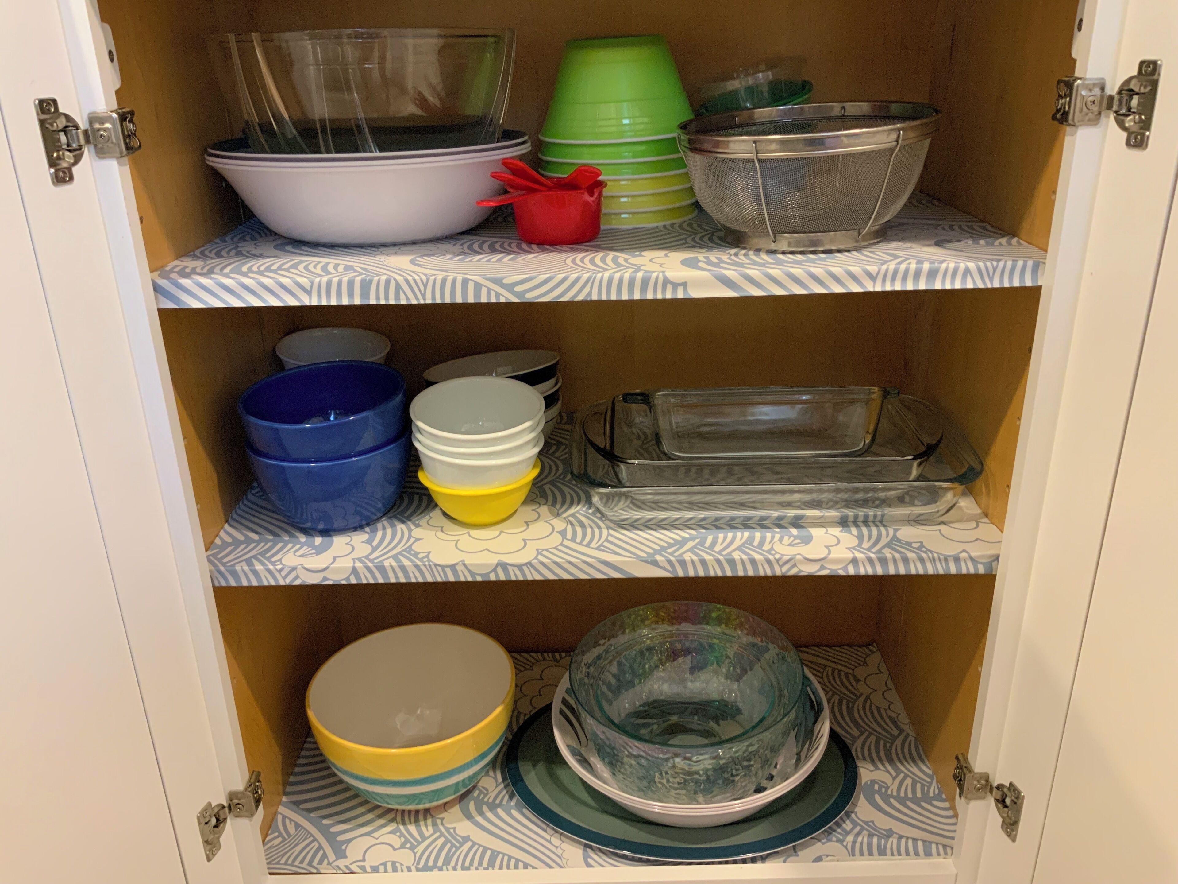 Un mobile contenitore con ripiani che ospitano diversi utensili da cucina.